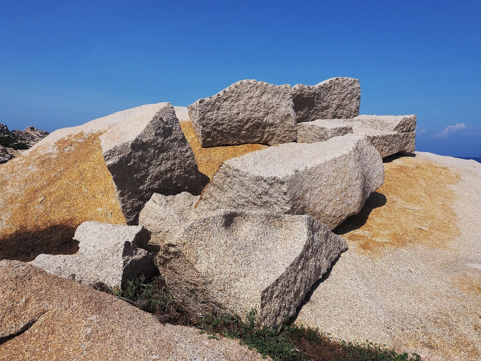 Roccia di granito modellata dal vento con cavità a tafoni, circondata da macchia mediterranea